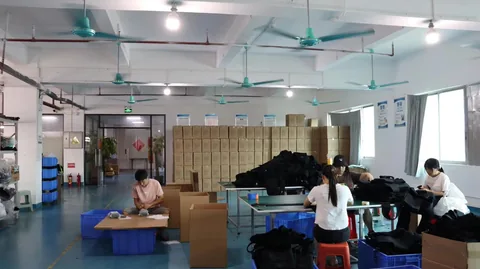 Mesas de trabajo y cajas de cartón en un área de inspección y embalaje de fábrica.