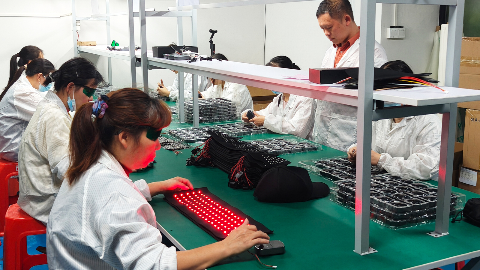 Staff working on red light components along assembly benches.