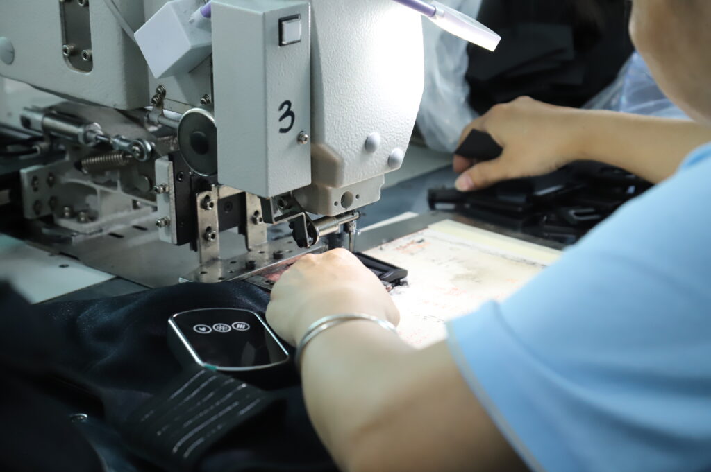 Hands guiding a flexible product component through a sewing machine