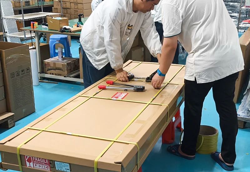 Trabajadores sujetando una caja grande de transporte con flejes