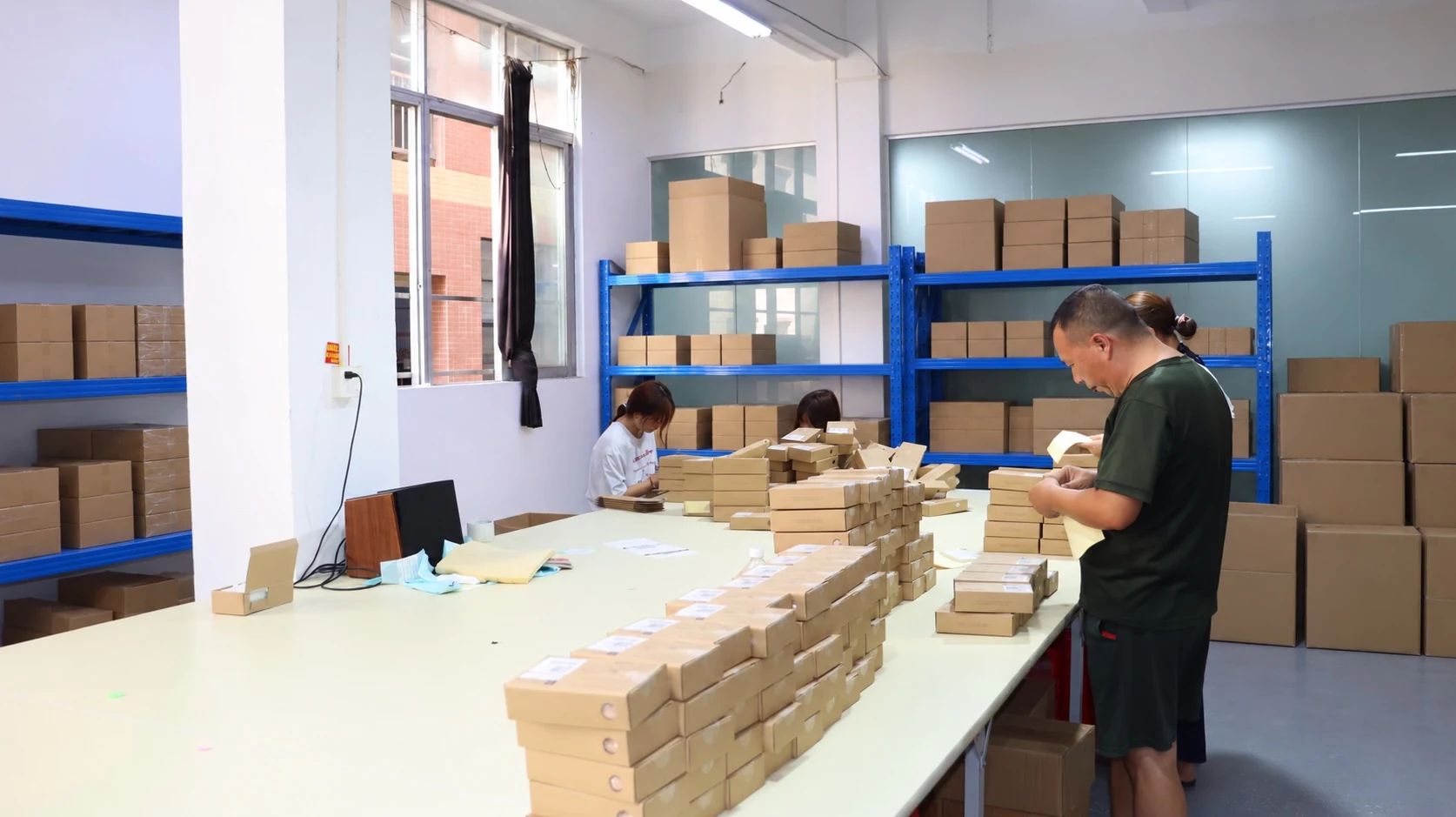 Staff preparing products and cartons at a packaging workbench