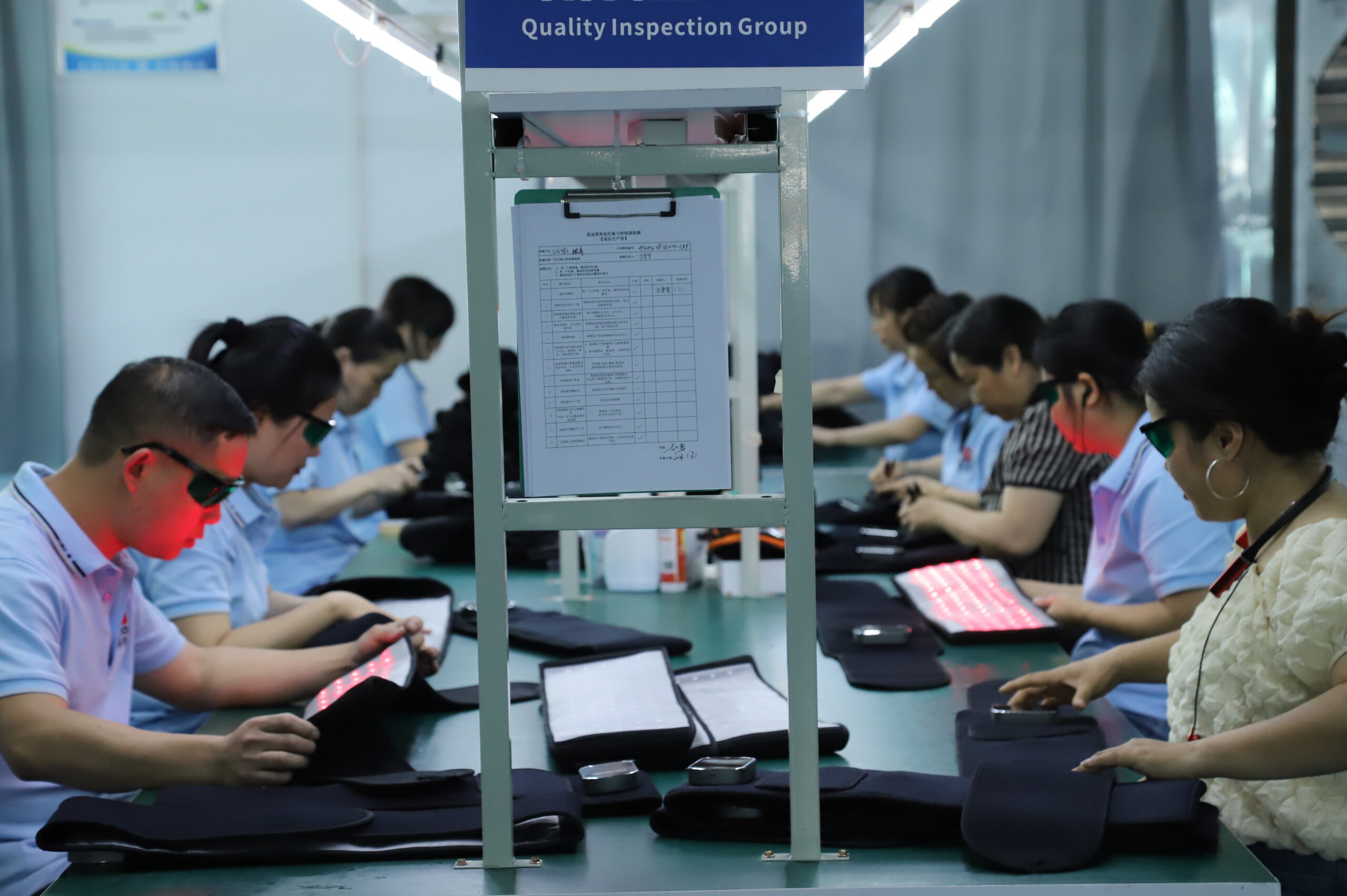 Staff checking illuminated flexible light products at facing workstations